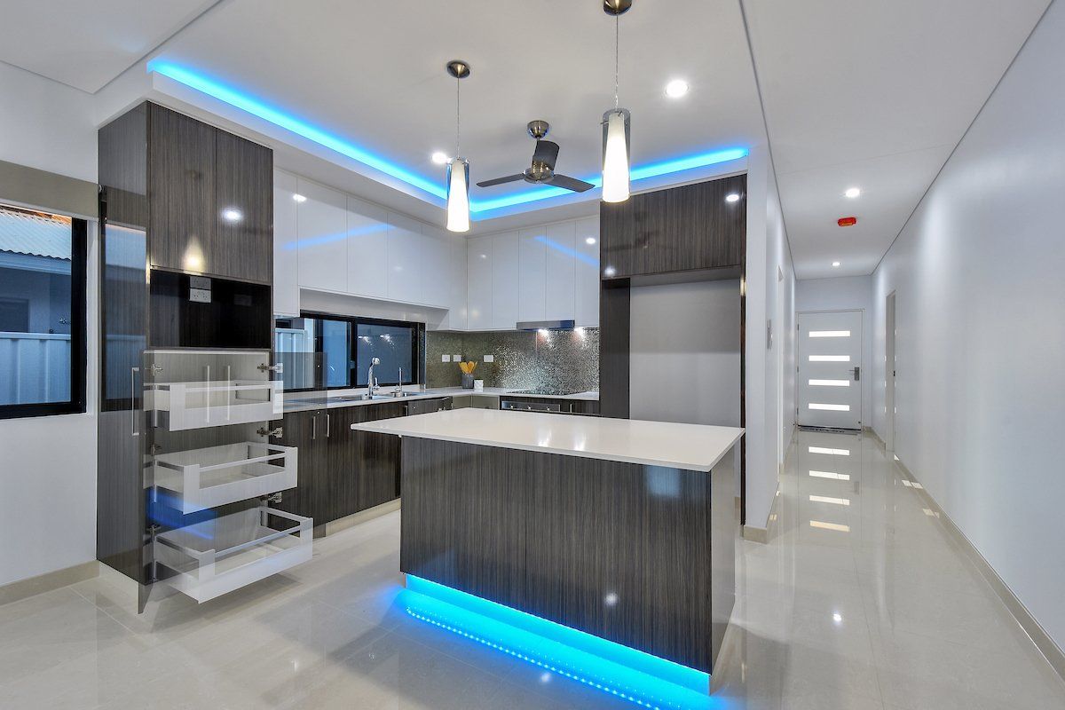 A kitchen with a large island and blue lights on the ceiling