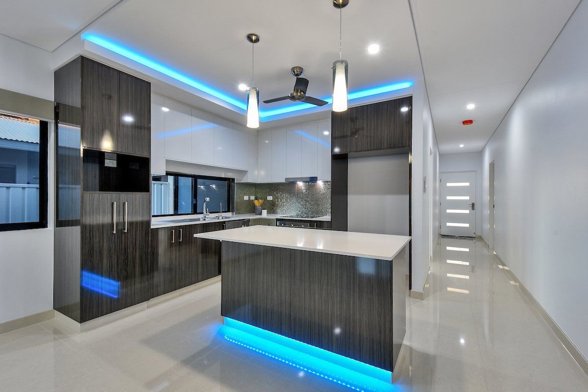 A kitchen with a large island and blue lights on the ceiling