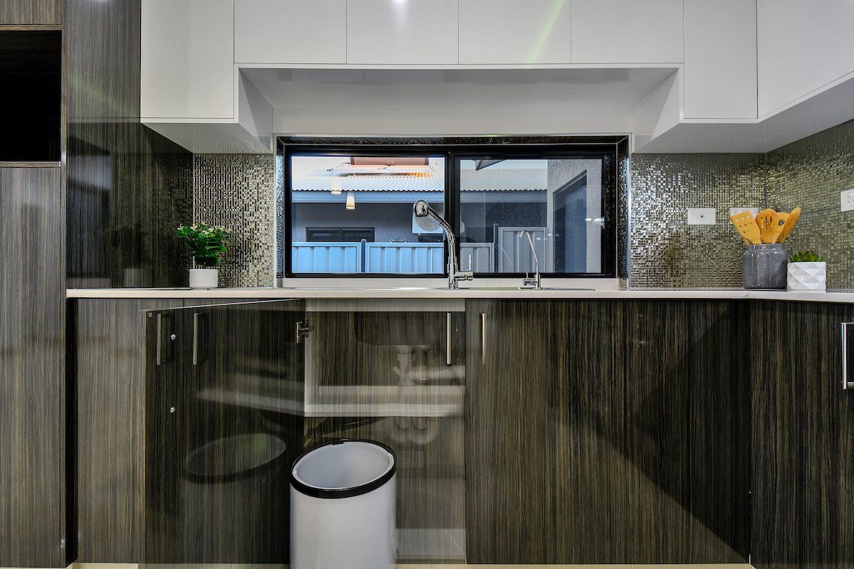 A kitchen with a trash can and a window.