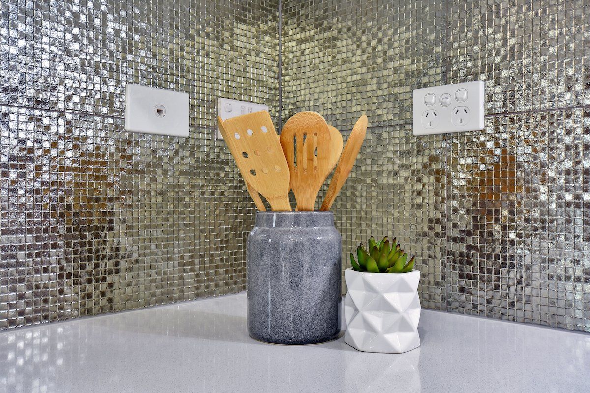 A pot of wooden utensils is sitting on a counter next to a potted plant.