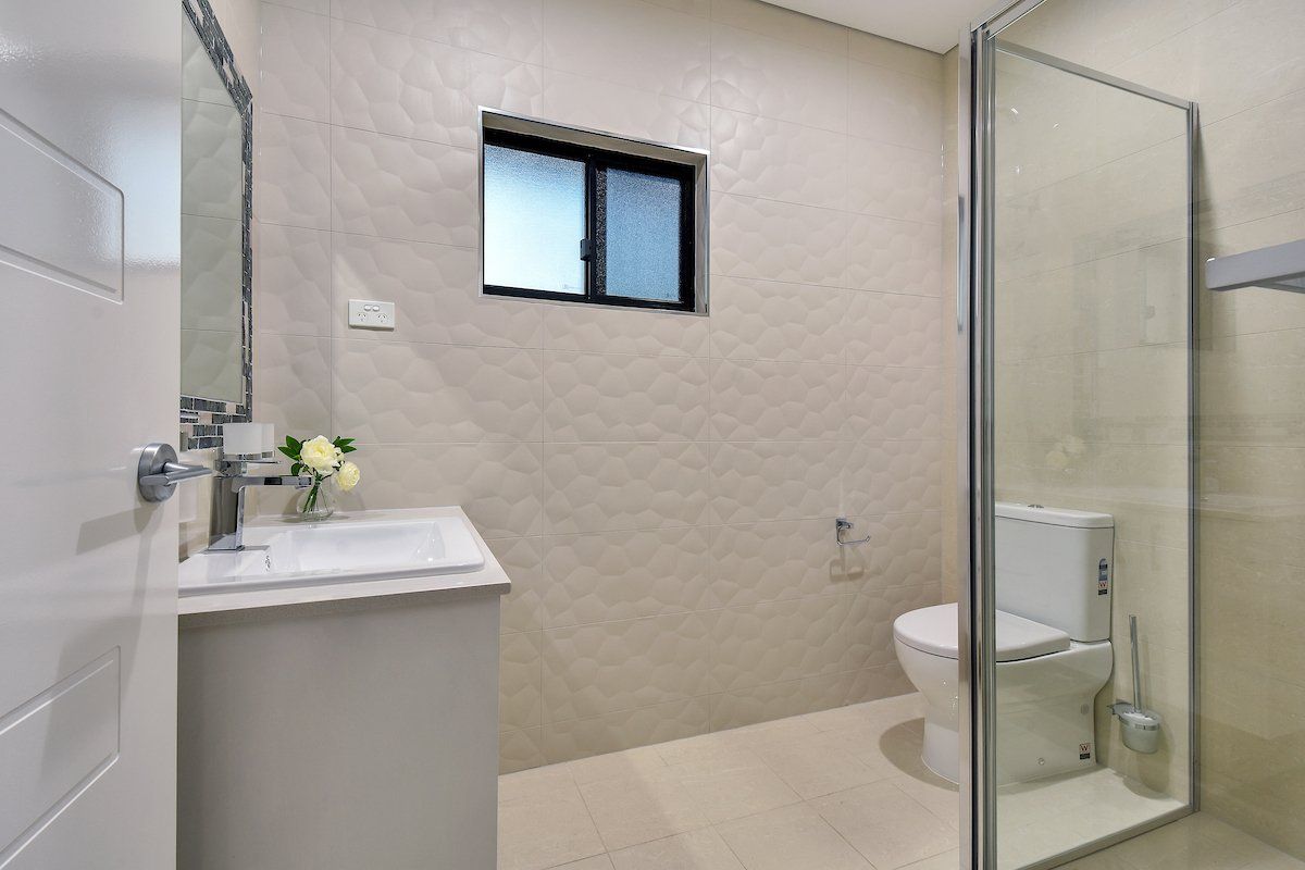 A bathroom with a toilet , sink and shower.