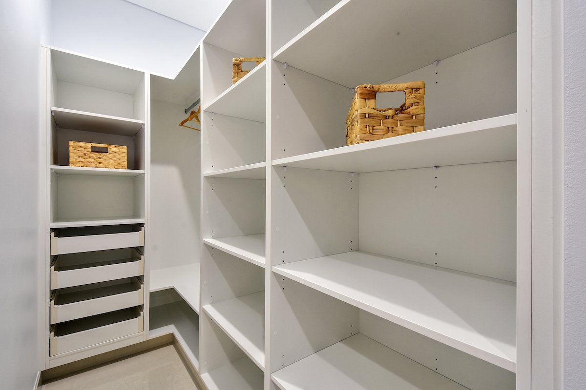 A walk in closet with lots of shelves and drawers.