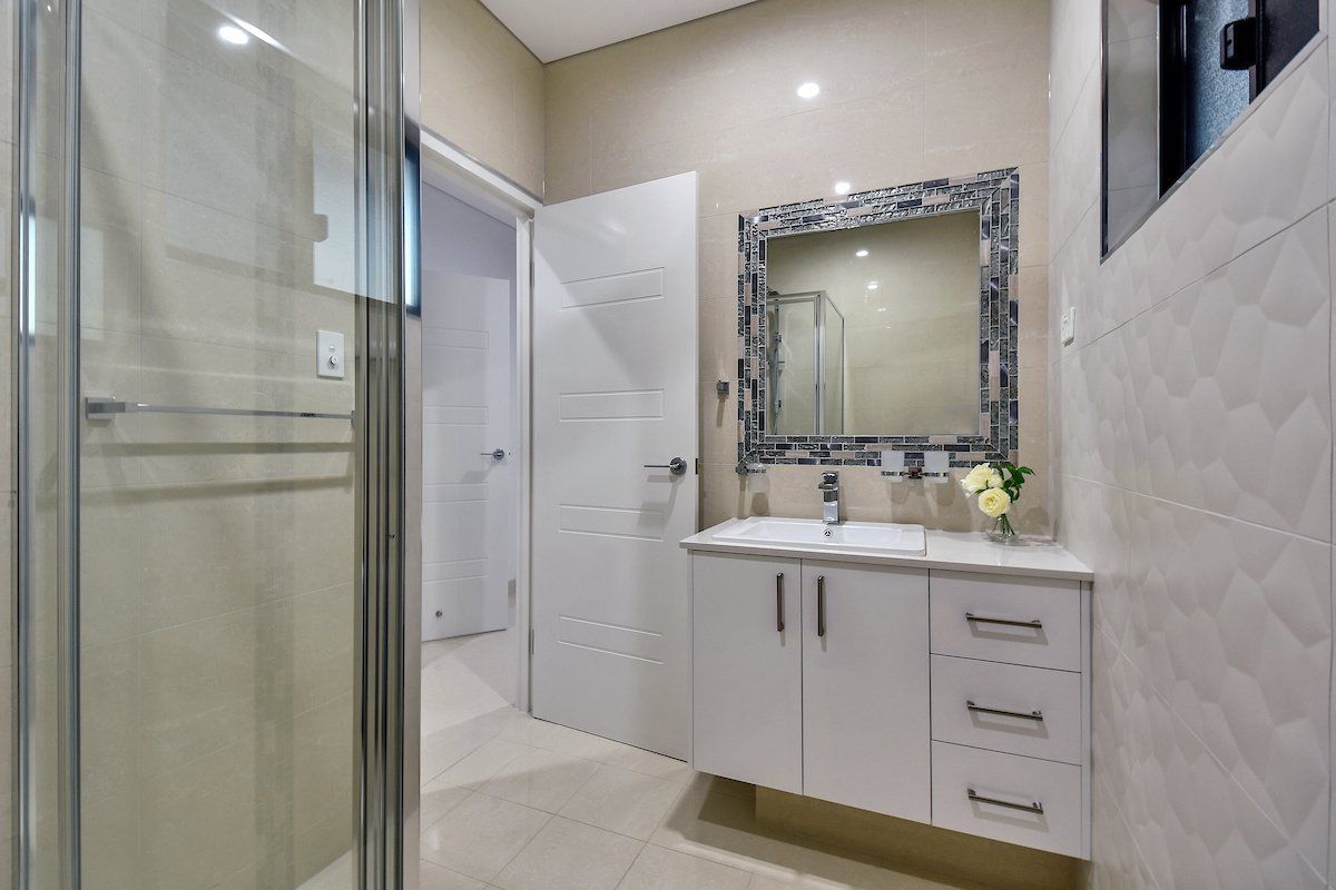 A bathroom with a sink , mirror and shower.