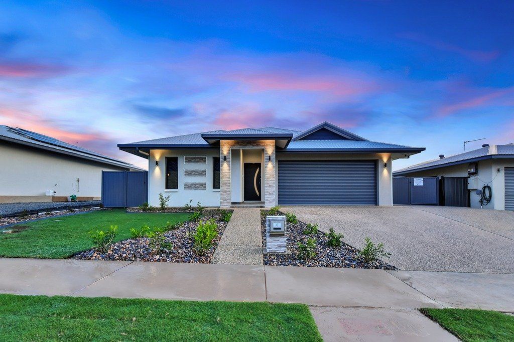 The front of a house with a large driveway and a lush green lawn.