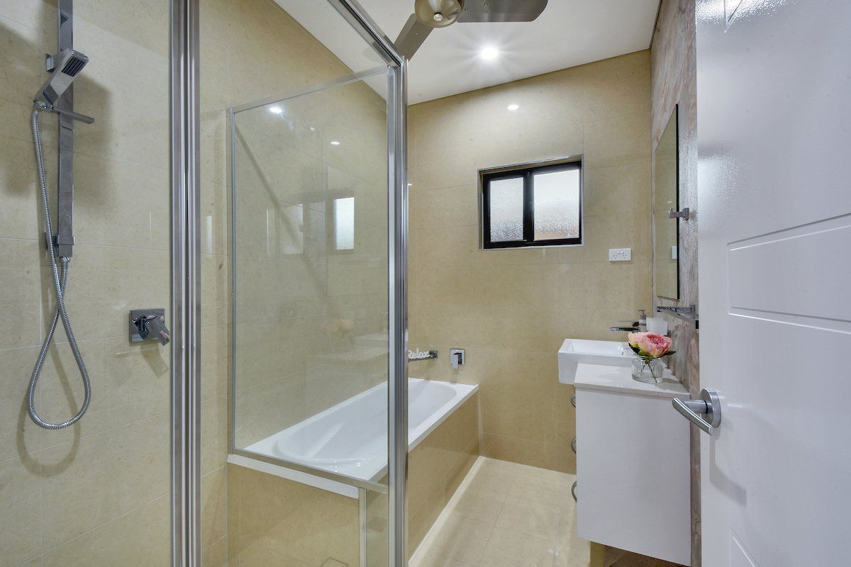 A bathroom with a bathtub , sink , shower and mirror.