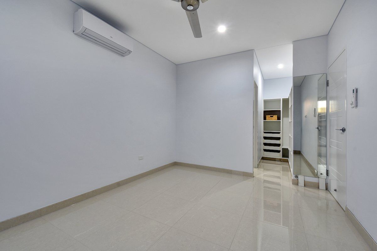 An empty room with a ceiling fan and a mirror.