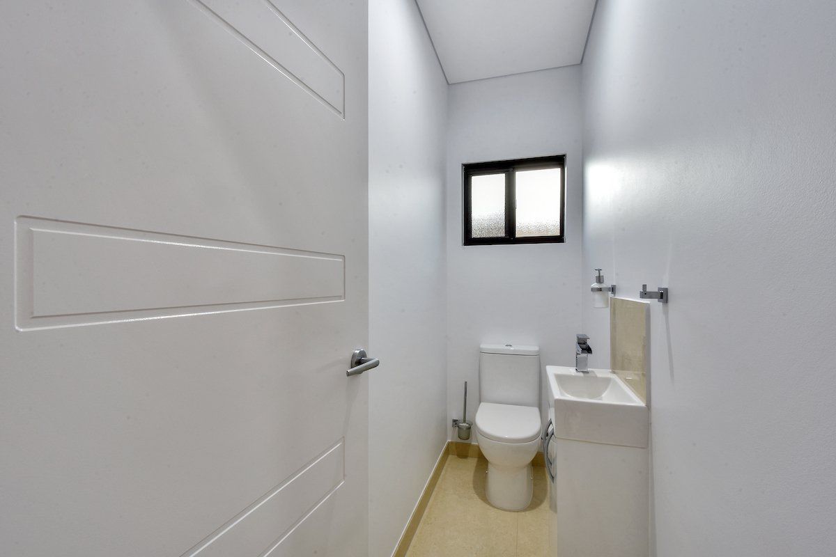 A bathroom with a toilet , sink and window.
