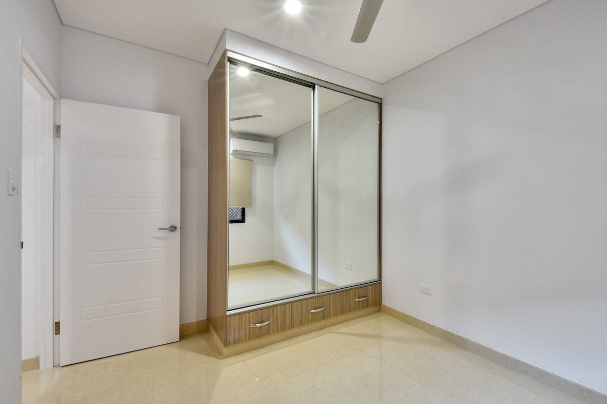 A bedroom with a large mirrored wardrobe and a ceiling fan