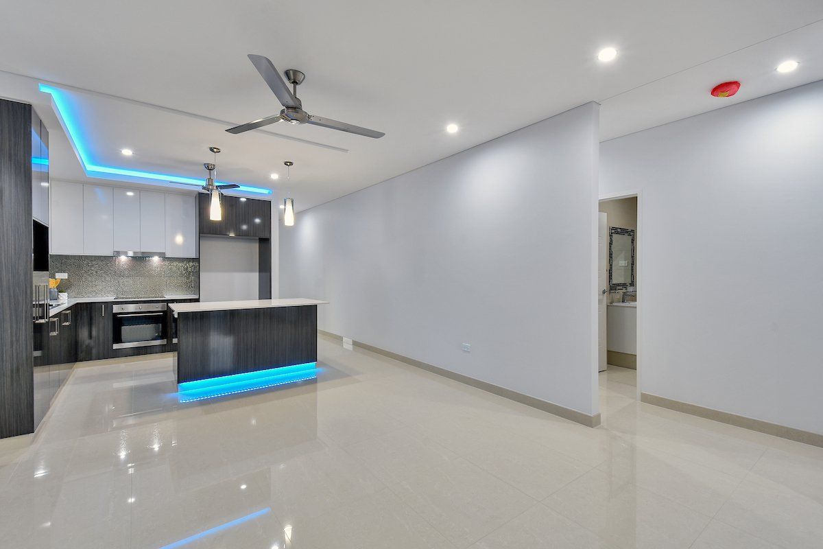 An empty kitchen with a ceiling fan and blue lights