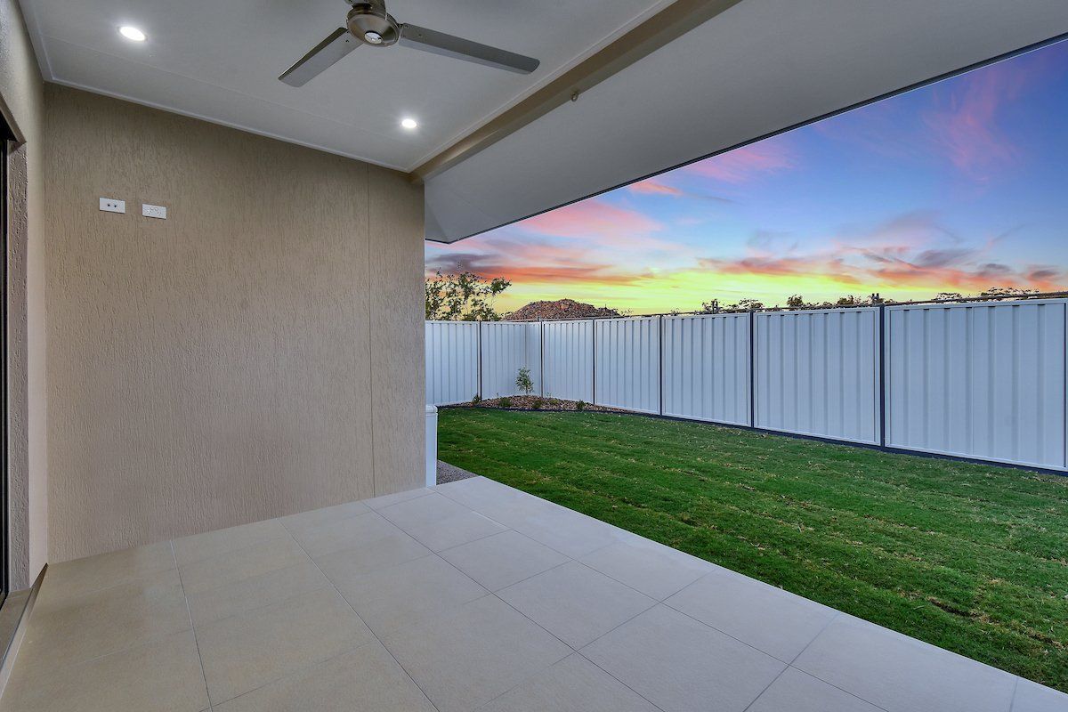 There is a patio with a ceiling fan and a fence in the background.