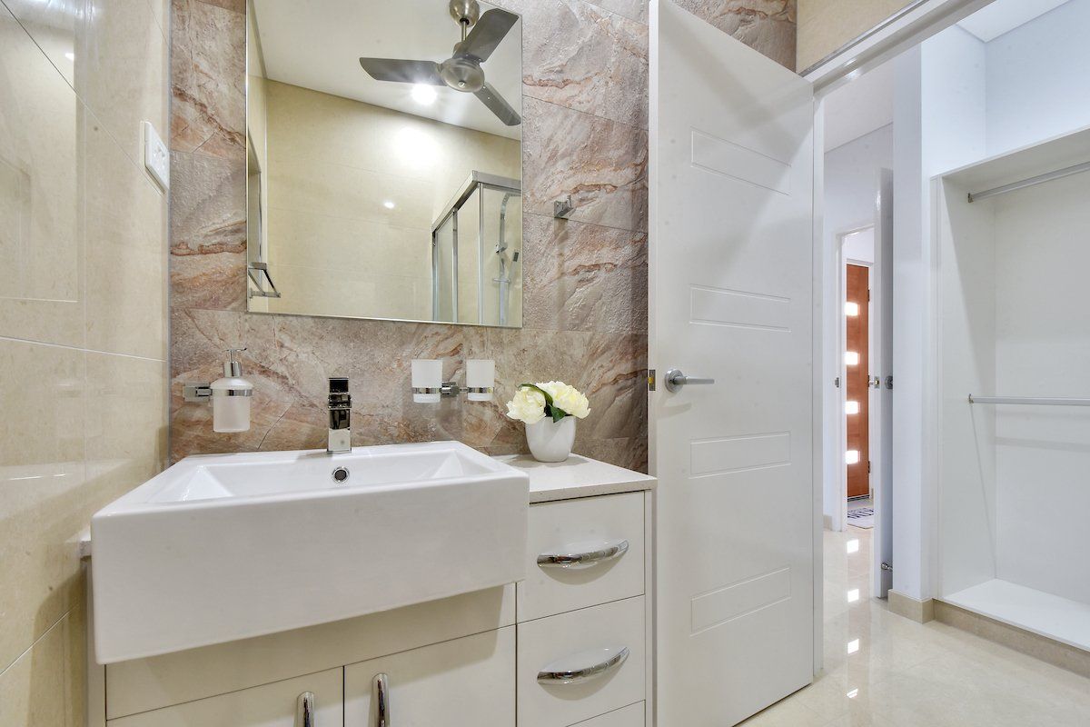 A bathroom with a sink , mirror and ceiling fan.