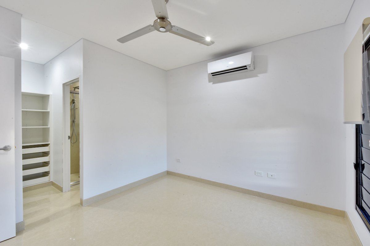 An empty bedroom with a ceiling fan and air conditioner.