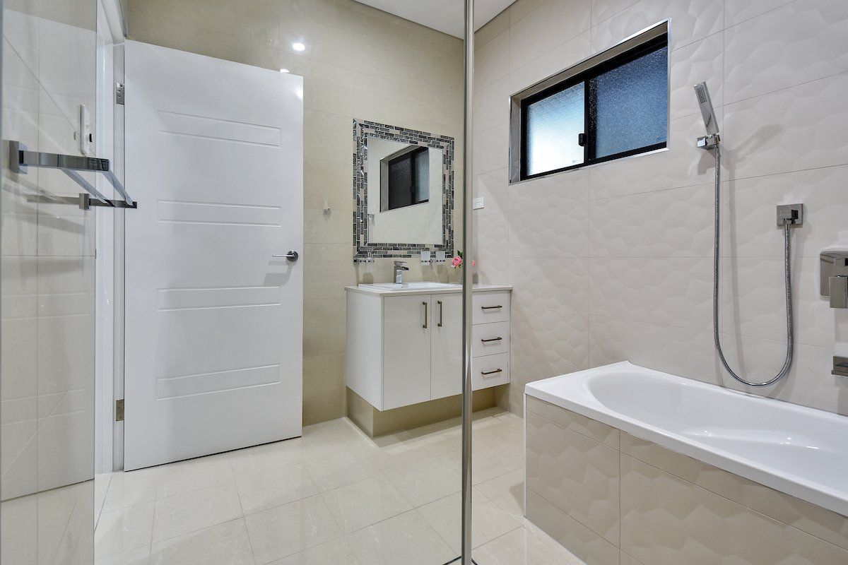 A bathroom with a tub , sink , mirror and shower.