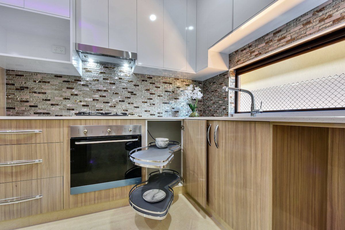 A kitchen with wooden cabinets , a stove , a sink , and a toilet.