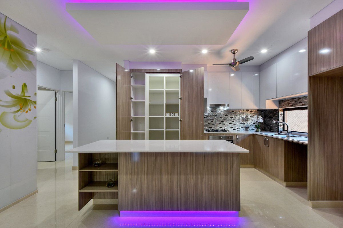 A kitchen with a large island and purple lights on the ceiling