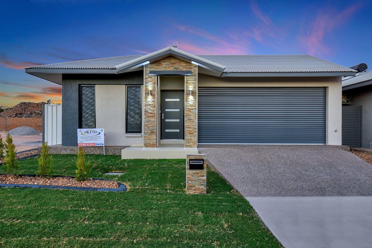 A modern house with a large garage and a sign in front of it.