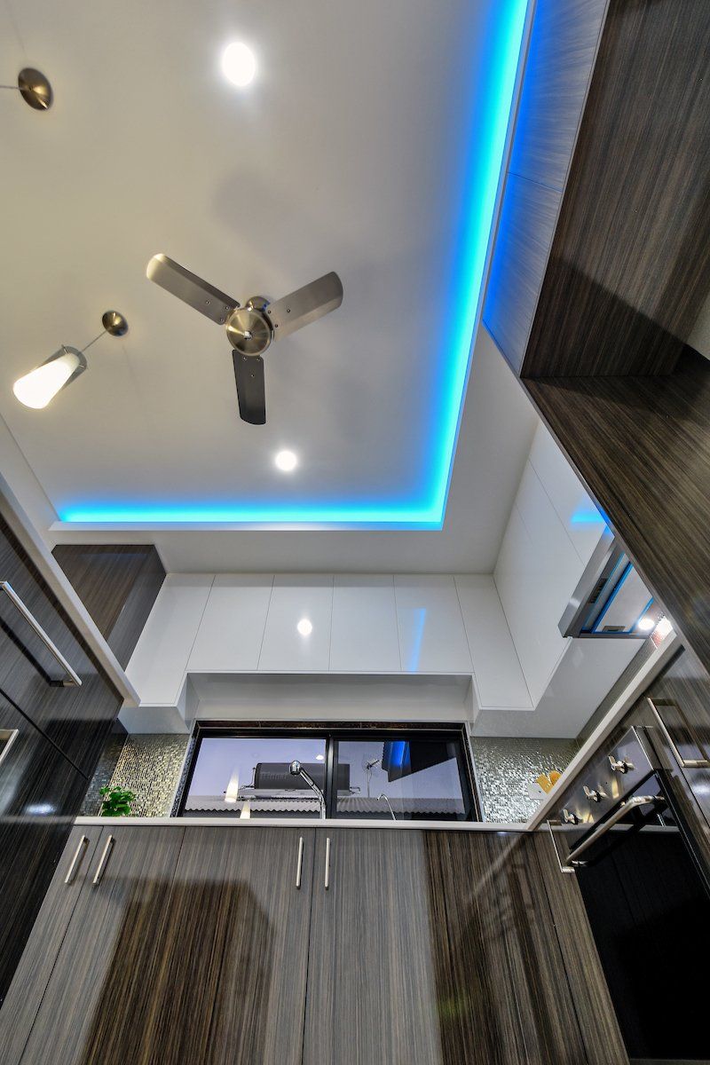 A kitchen with a ceiling fan and blue lights