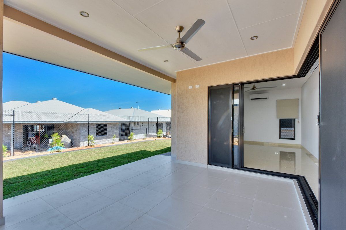 An empty patio with a ceiling fan and sliding glass doors.