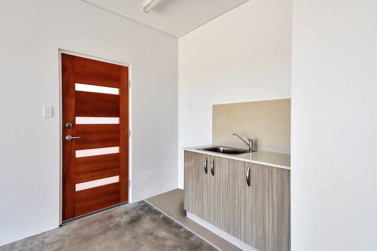 A kitchen with a sink , cabinets and a wooden door.