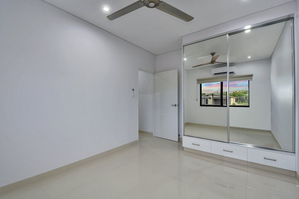 An empty bedroom with a ceiling fan and a large mirrored wardrobe.