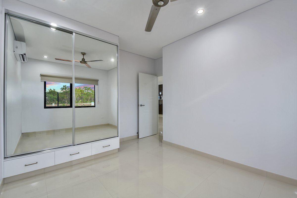 An empty bedroom with a large mirrored wardrobe and a ceiling fan.