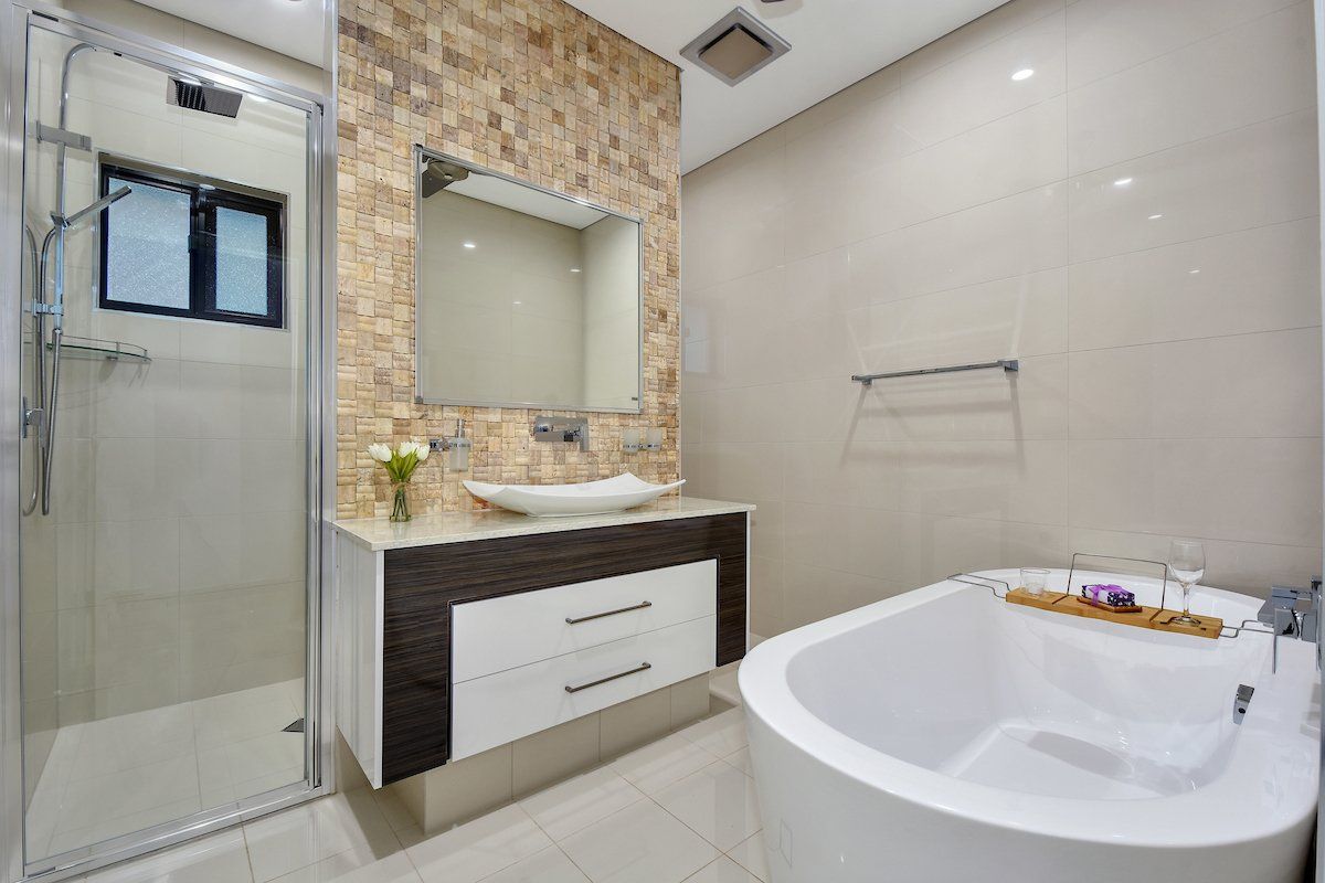 A bathroom with a tub , sink , mirror and shower.