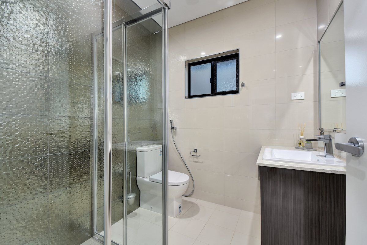 A bathroom with a toilet , sink and shower.