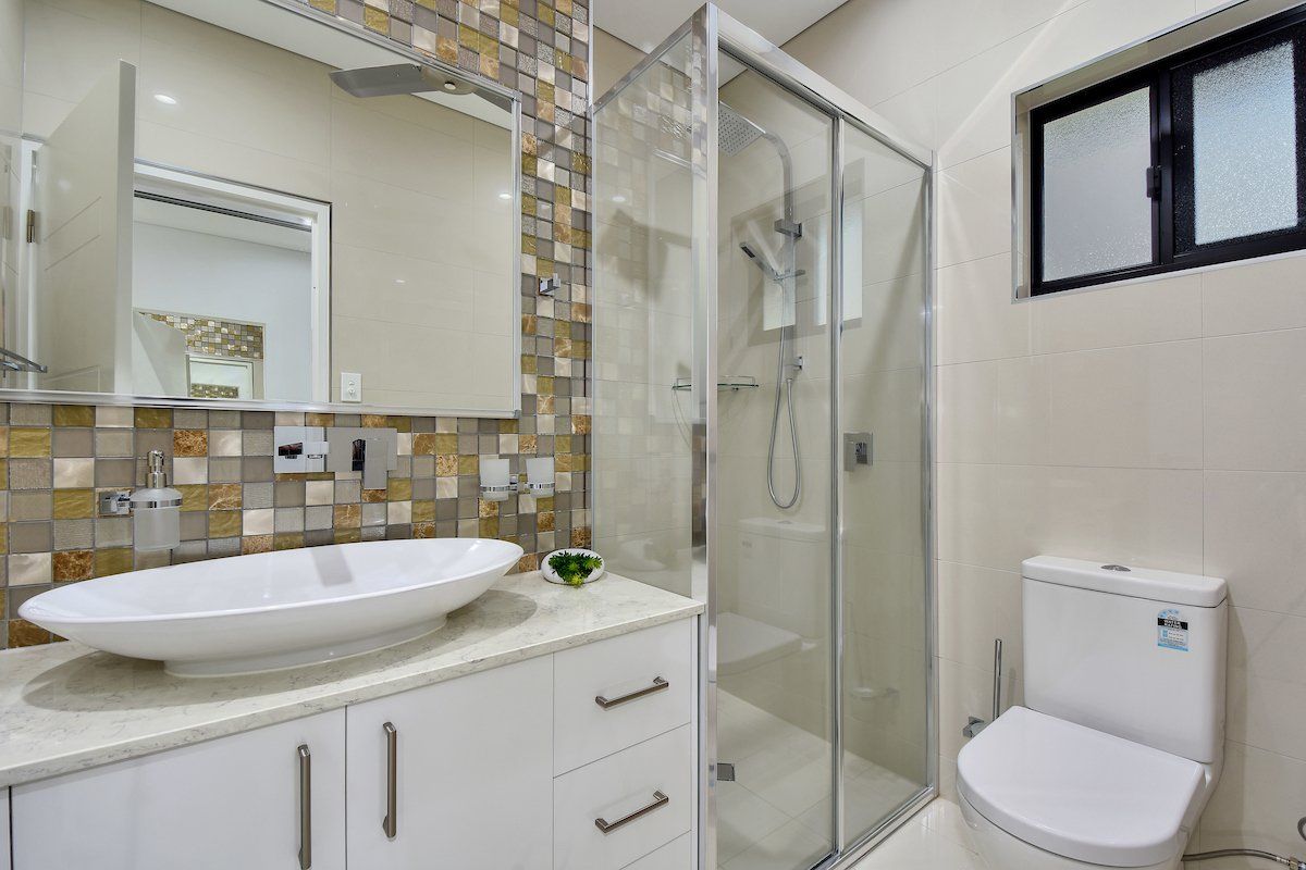 A bathroom with a sink , toilet , shower and mirror.
