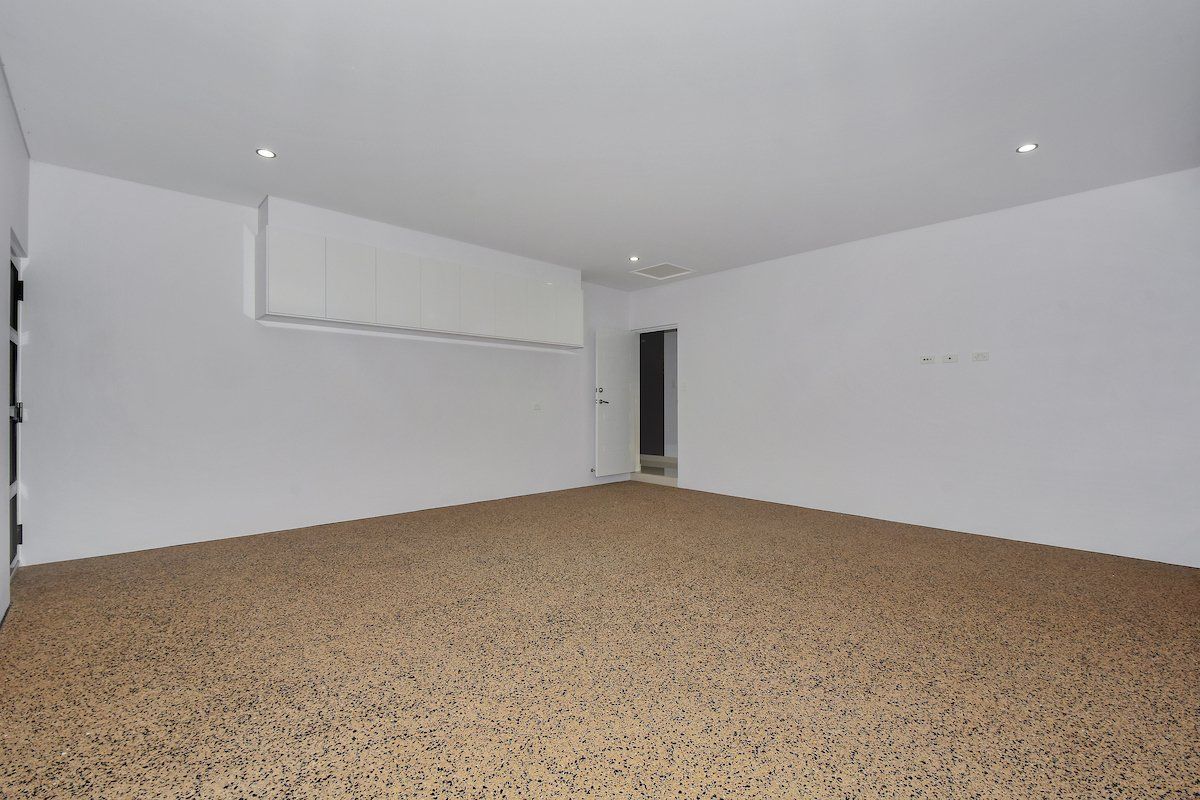 An empty garage with a carpeted floor and white walls