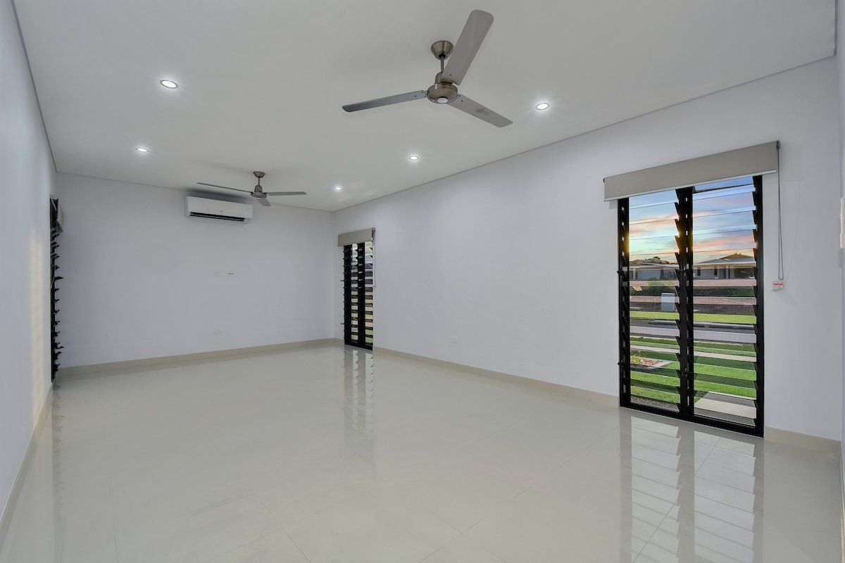 A large empty room with a ceiling fan and sliding glass doors.