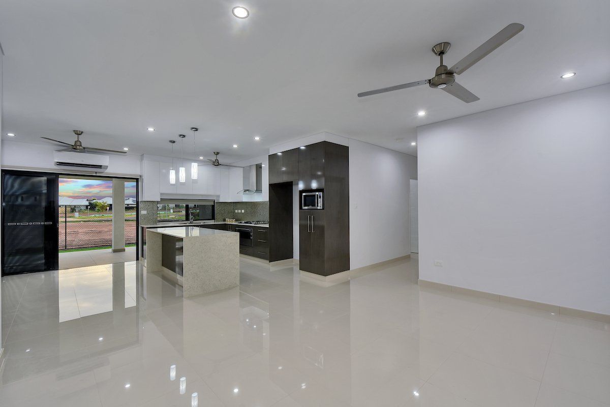 An empty room with a ceiling fan and a kitchen