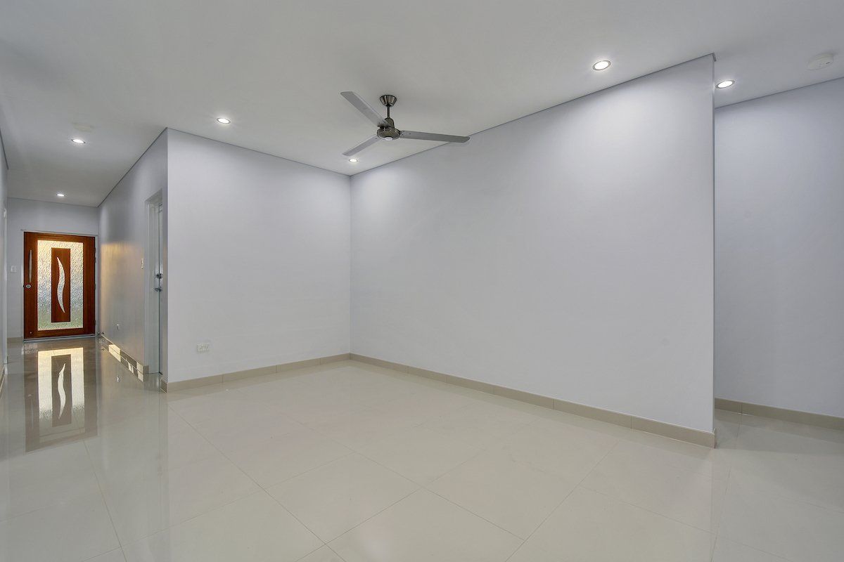 An empty room with white walls and a ceiling fan.