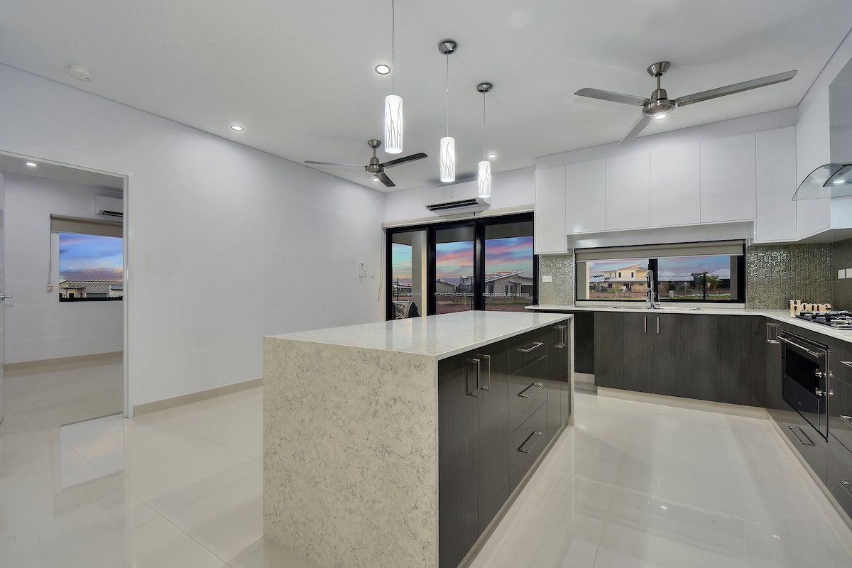 A kitchen with a large island and a ceiling fan.