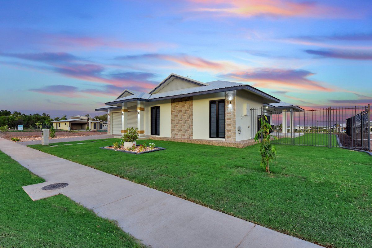 A house with a lush green lawn and a sidewalk in front of it.