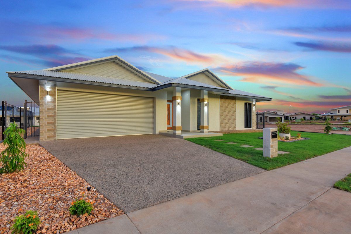 A large white house with a driveway and a sunset in the background.
