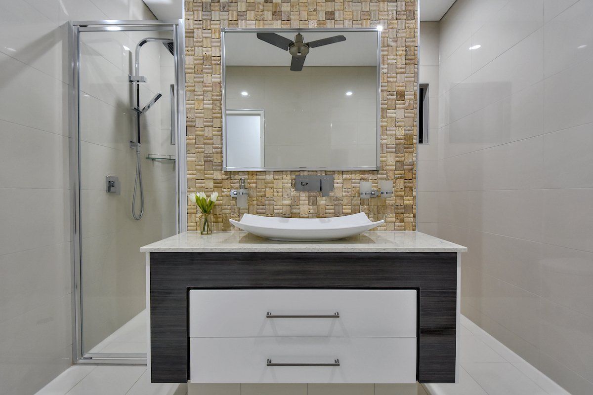 A bathroom with a sink , mirror and shower.