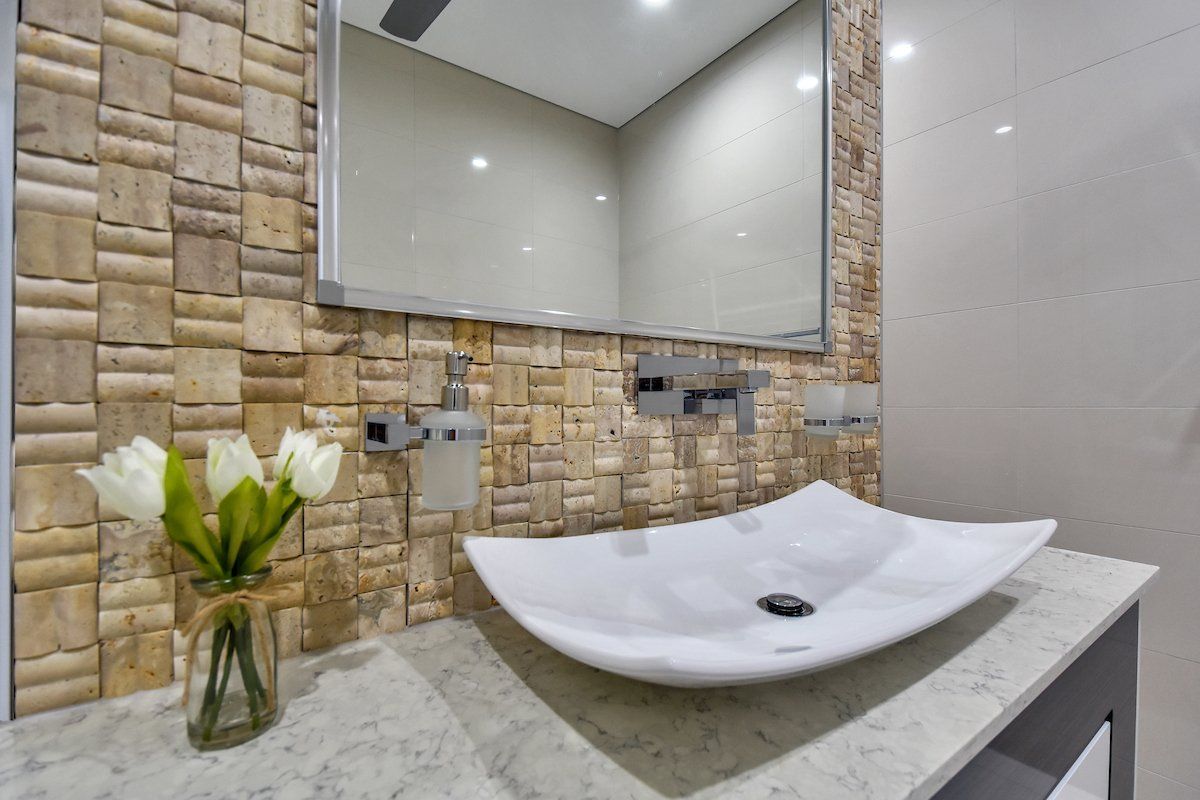 A bathroom with a sink , mirror and vase of flowers.