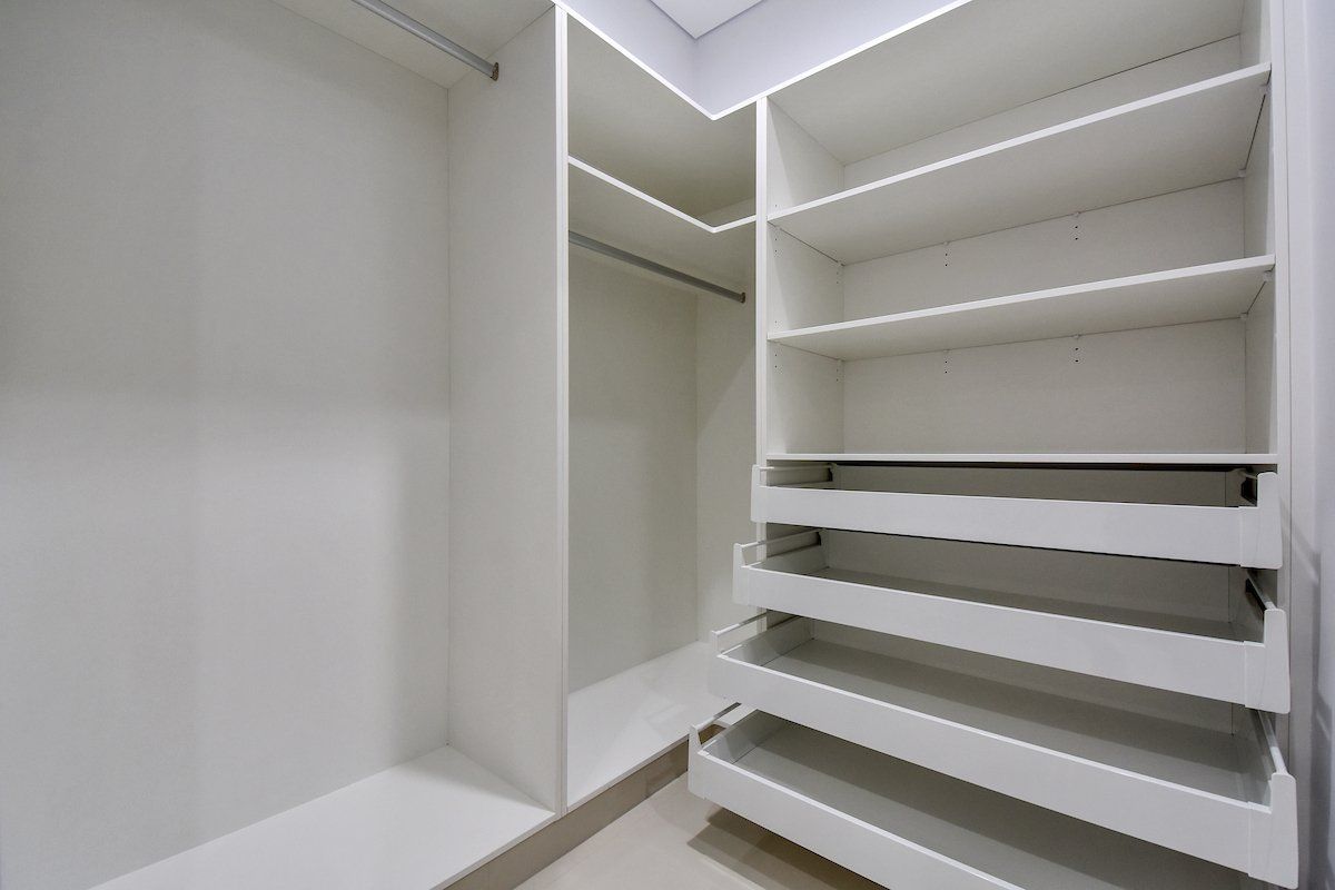 An empty walk in closet with lots of shelves and drawers.