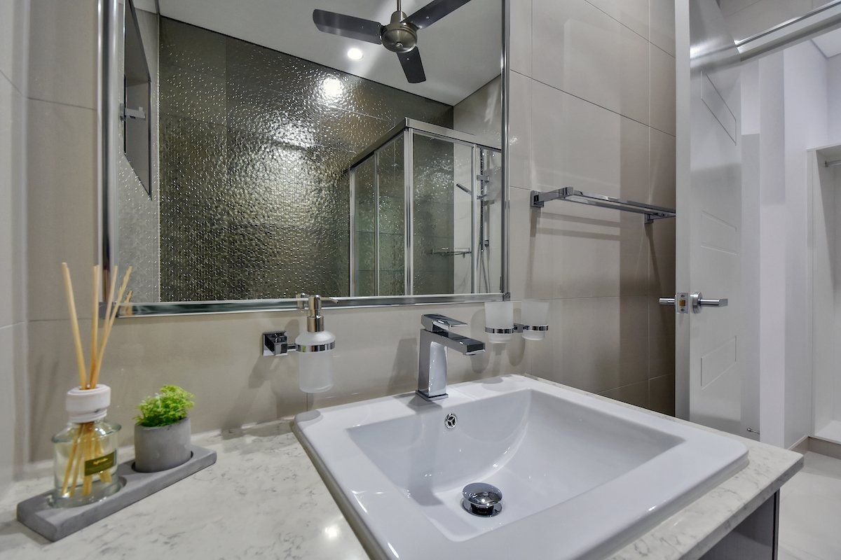 A bathroom with a sink , mirror and ceiling fan.