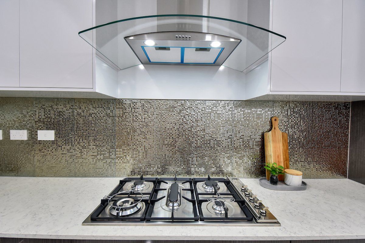 A kitchen with a stove top oven and a hood above it.