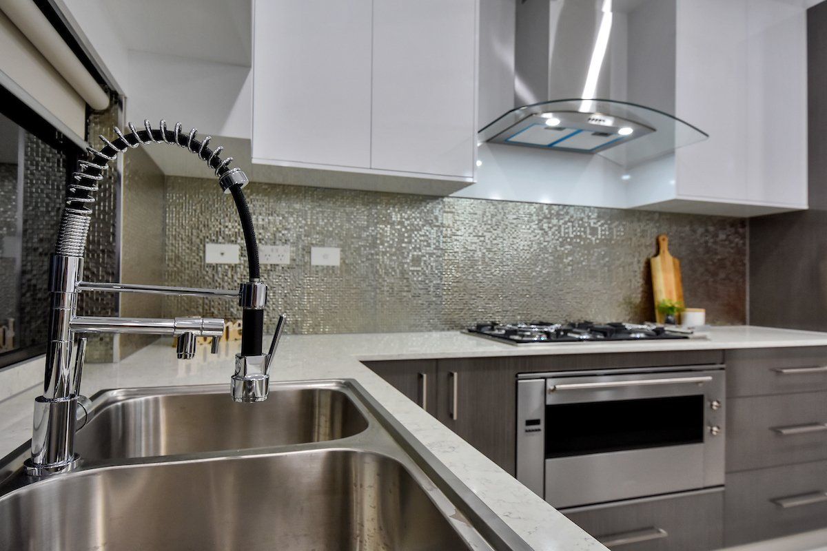 A kitchen with a stainless steel sink and a stove top oven