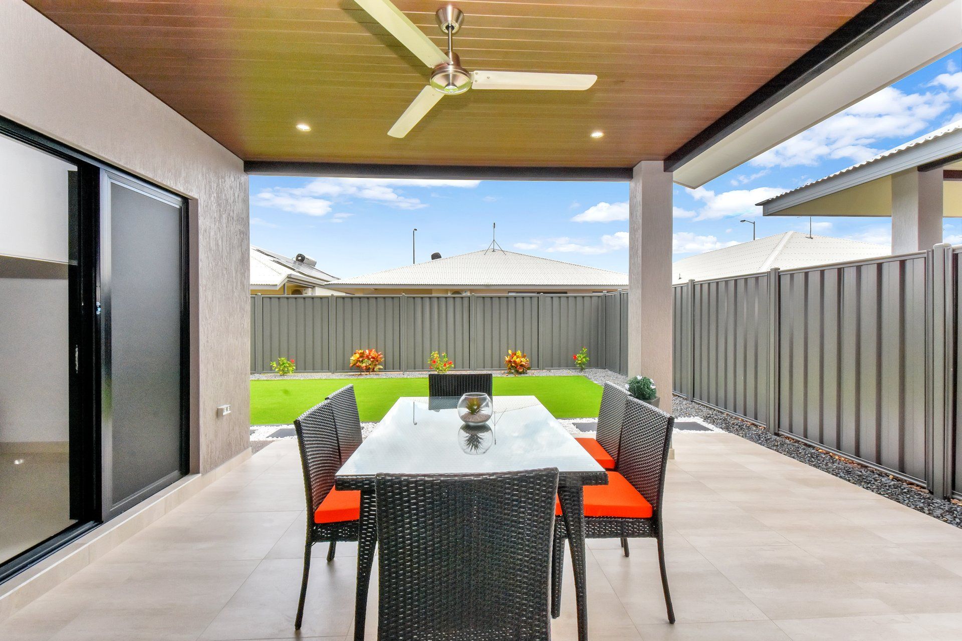 A patio with a table and chairs and a ceiling fan.