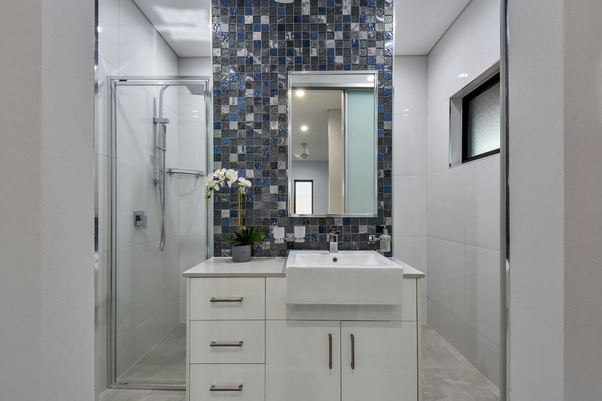 A bathroom with a sink , mirror and shower.