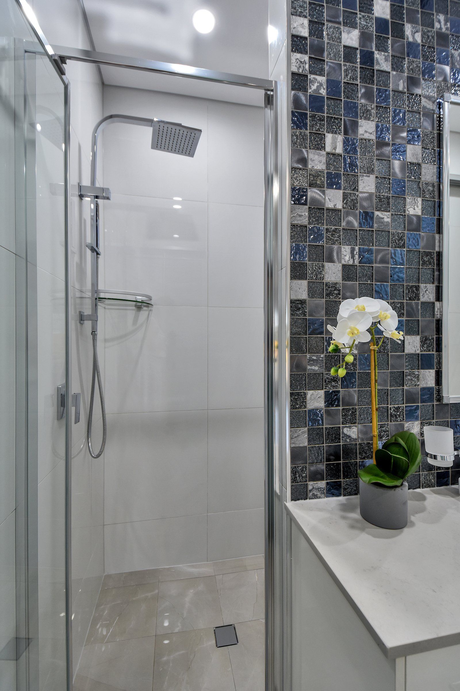 A bathroom with a walk in shower and a sink.