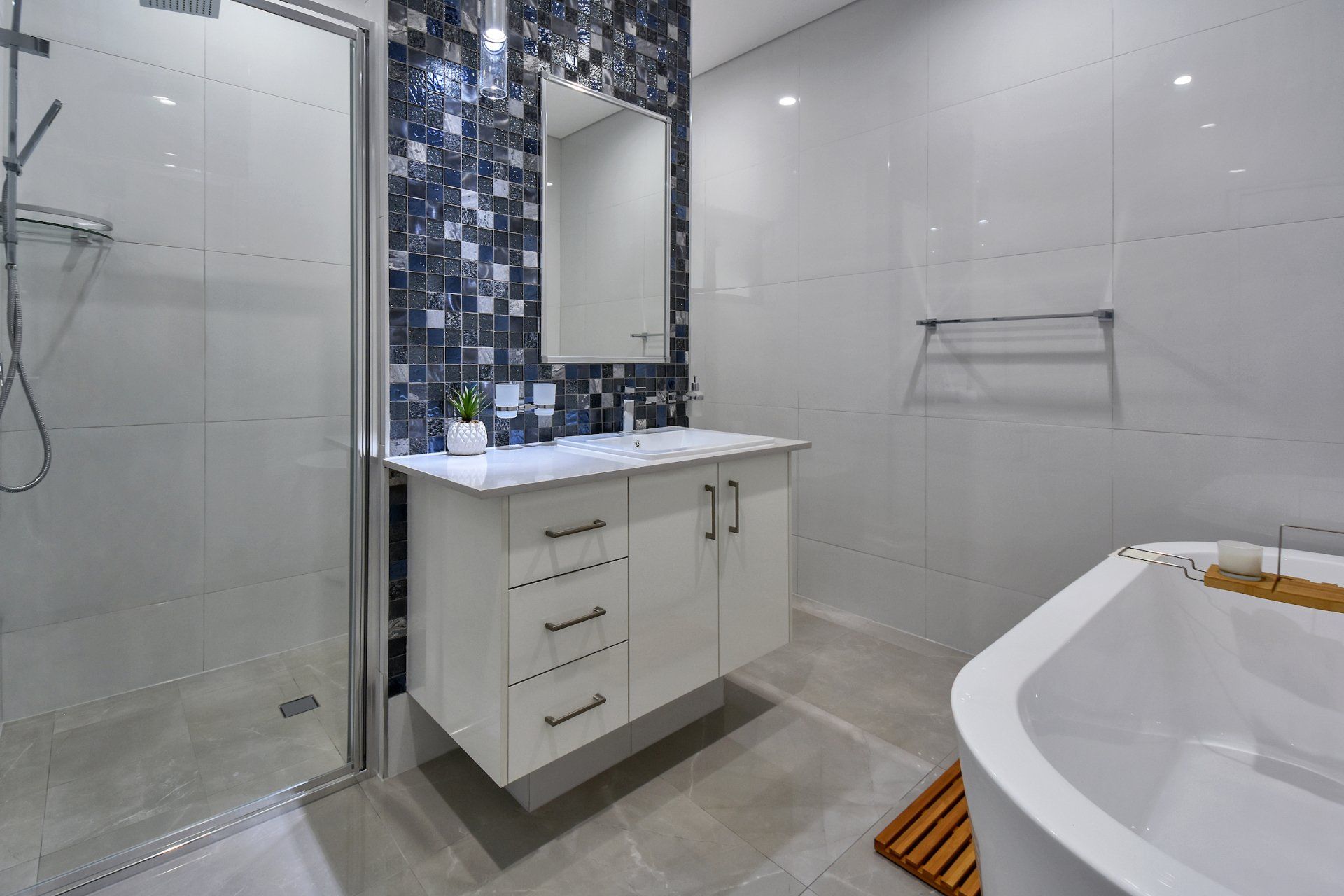 A bathroom with a sink , tub , shower and mirror.
