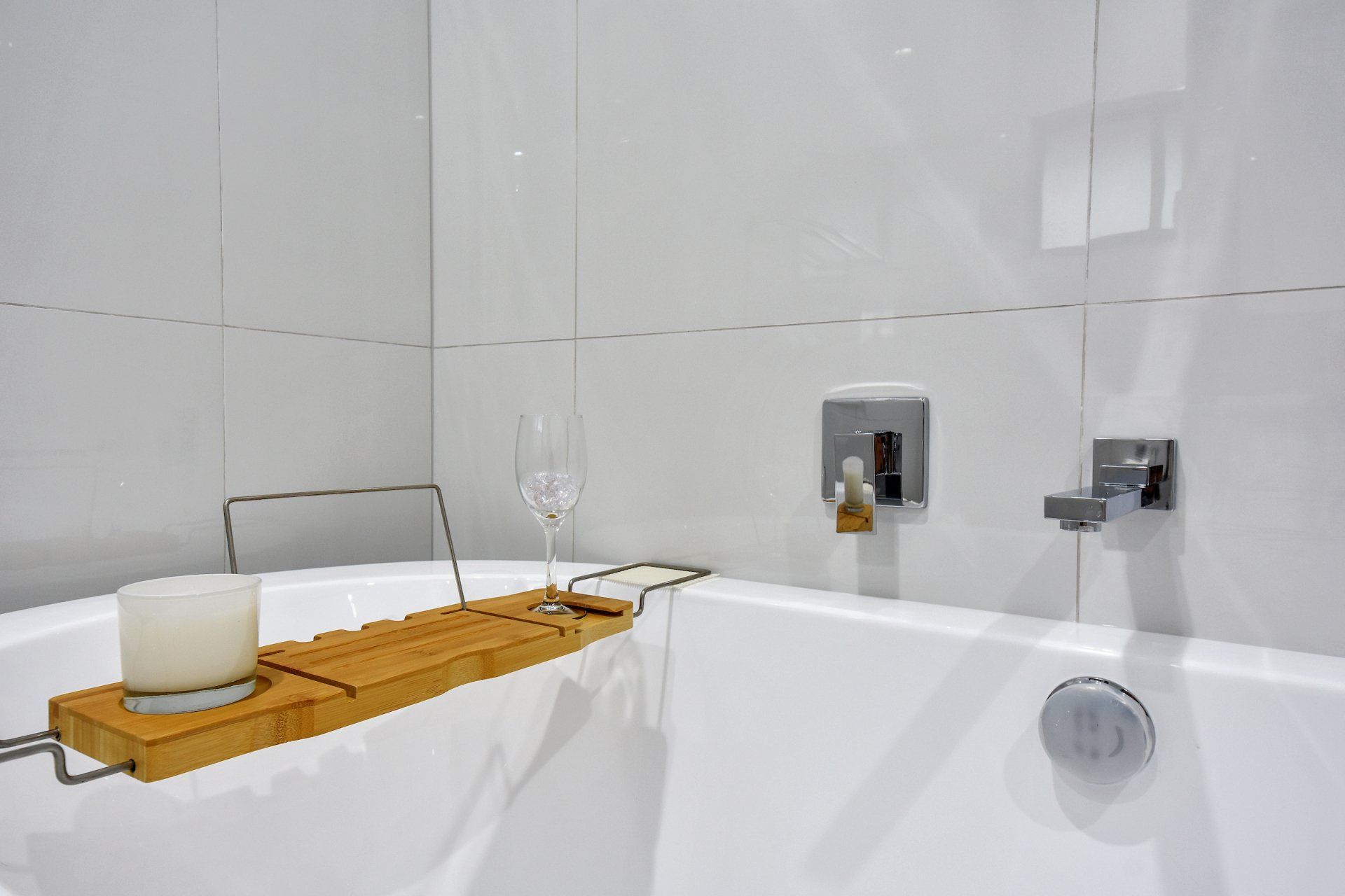 A bathtub with a wooden tray on top of it and a candle on it.