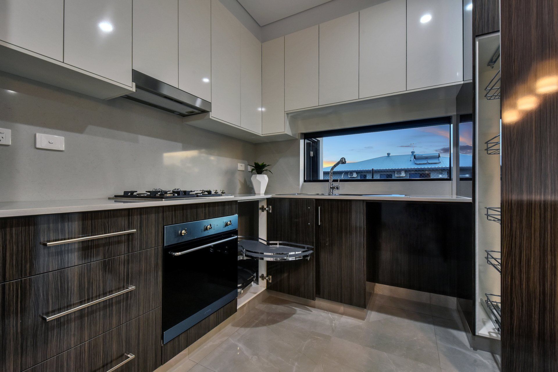 A kitchen with white cabinets and black appliances and a window