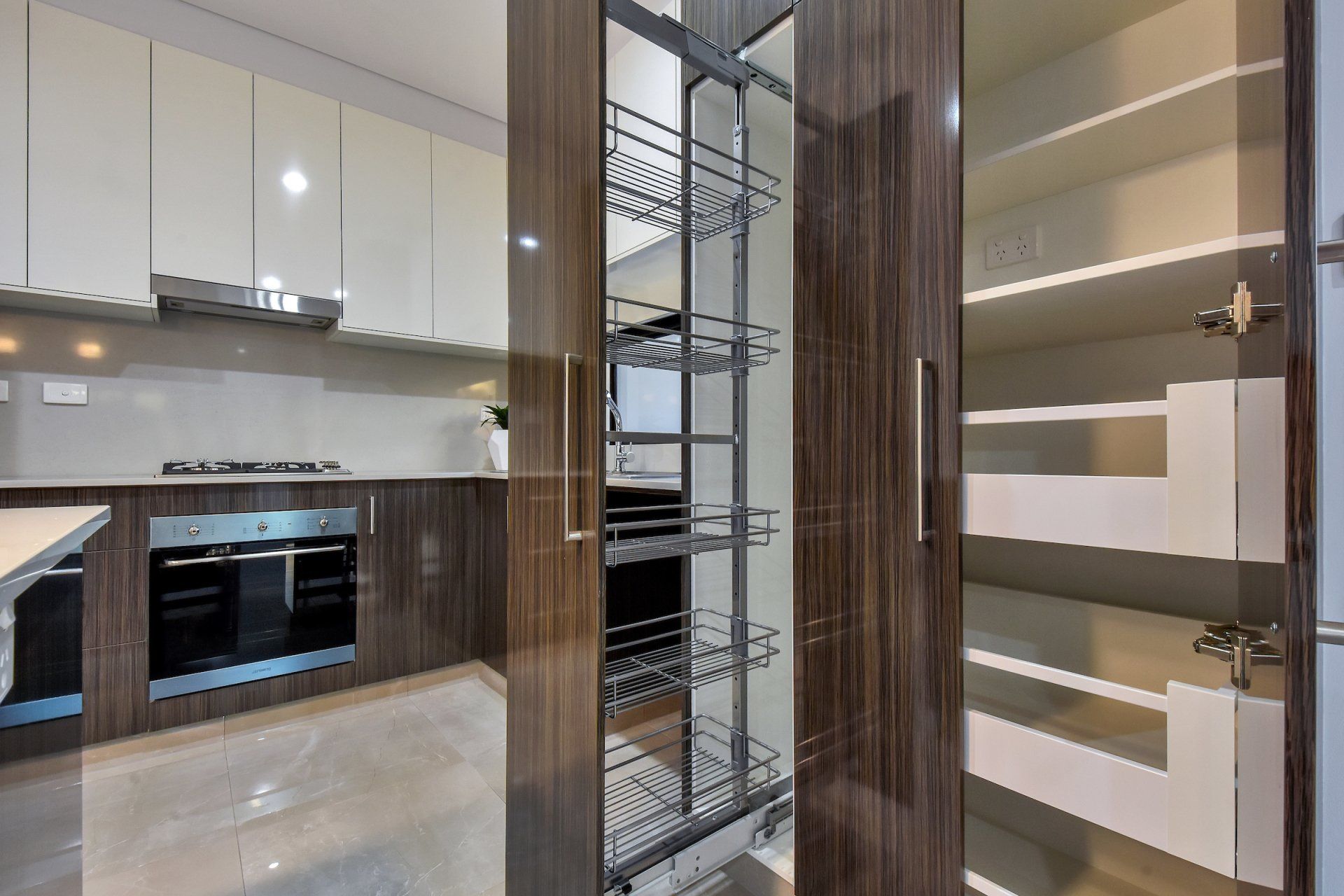 A kitchen with stainless steel appliances and a tall pantry.