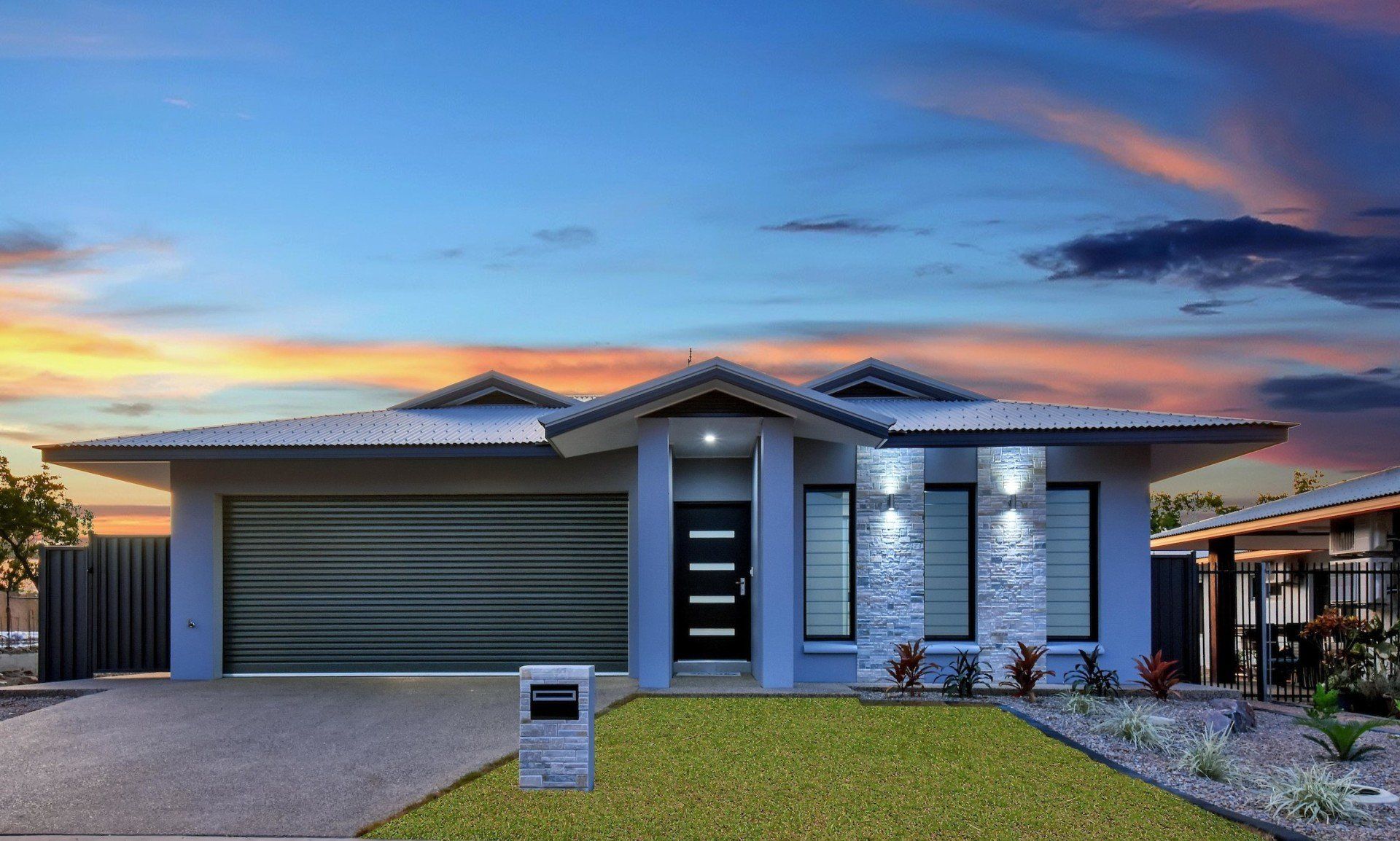 A house with a large garage and a sunset in the background