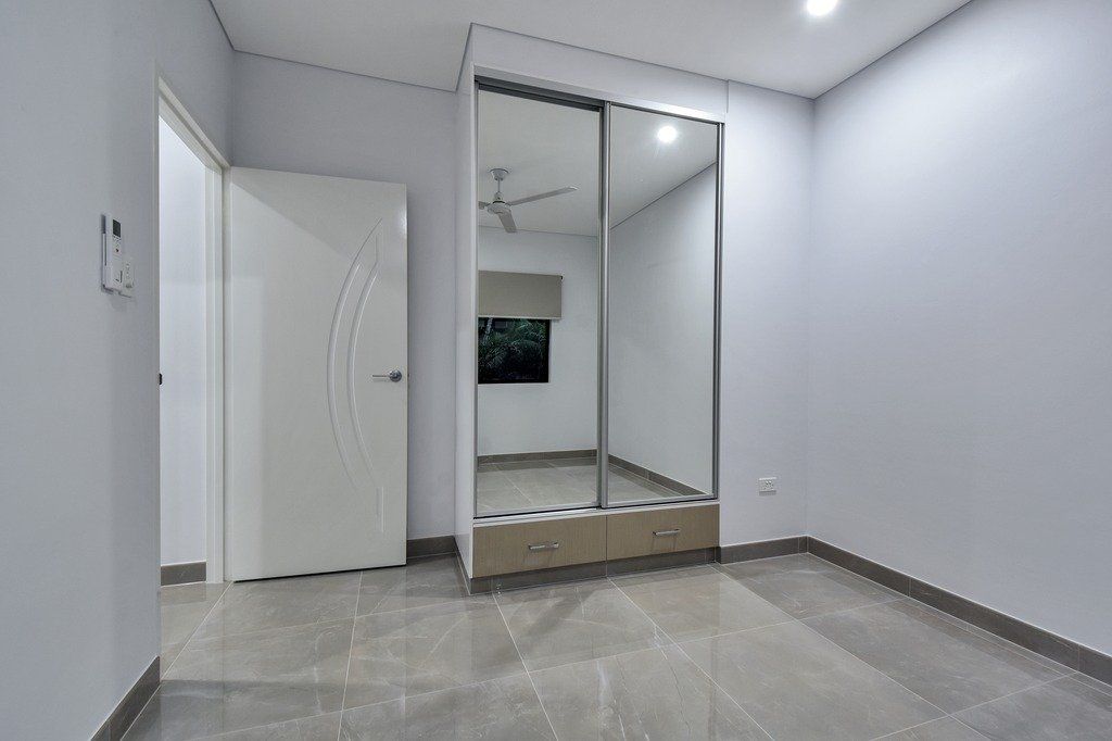 An empty bedroom with a large mirrored wardrobe and a ceiling fan.